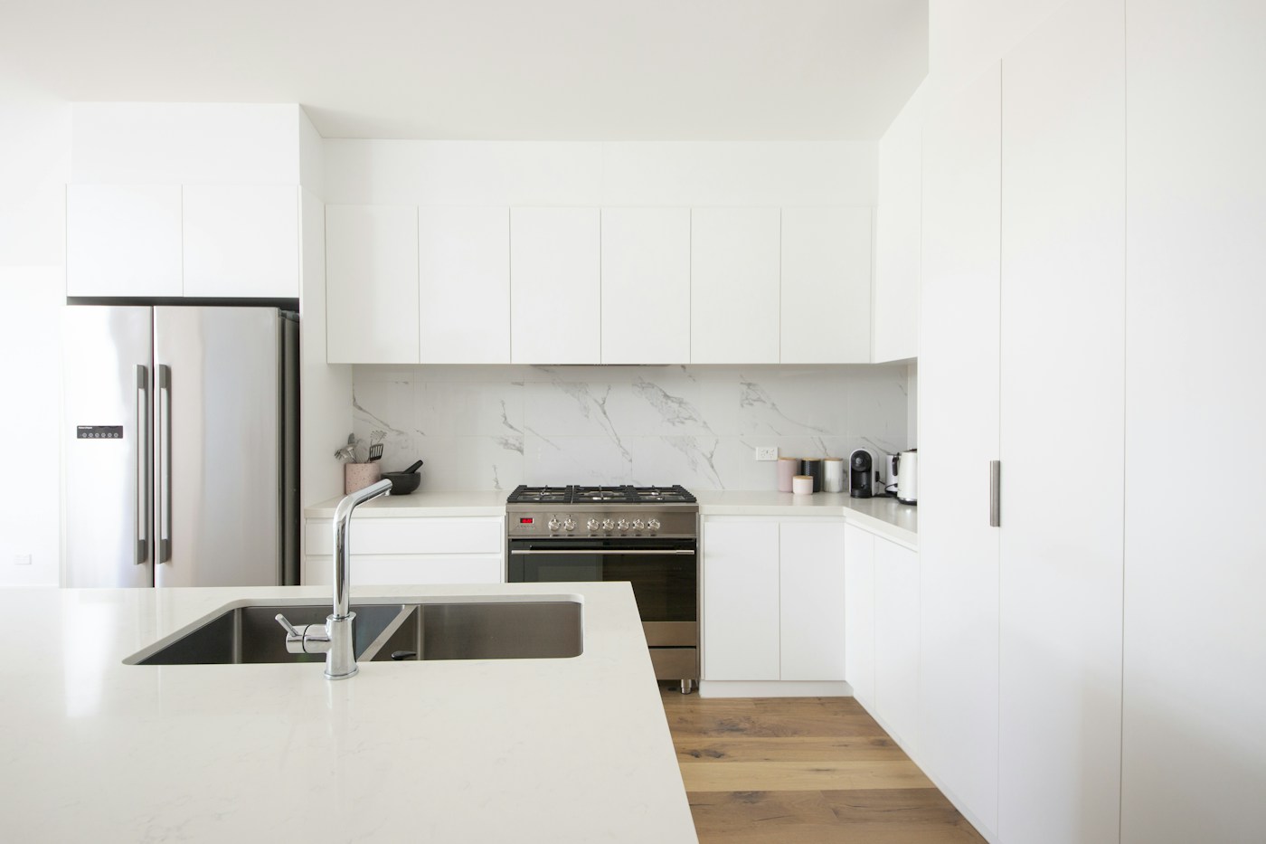 Bright white kitchen with a clean island and stainless steel appliances